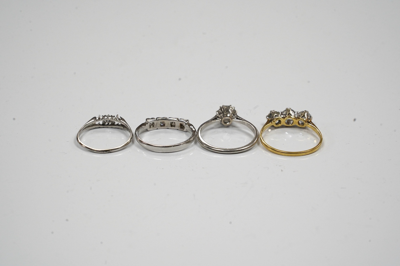 A 9ct gold and four stone diamond set ring, size L, a white metal and solitaire diamond ring and two simulated diamond rings. Condition - poor to fair